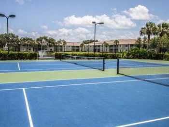 a tennis court with buildings in the background